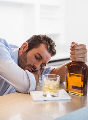 Drunk businessman clutching whiskey bottle asleep - Drug Addict Counseling